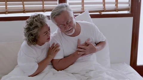 Asian elderly couple in bed, man's heart aches due to heart disease Stock Footage 153786450