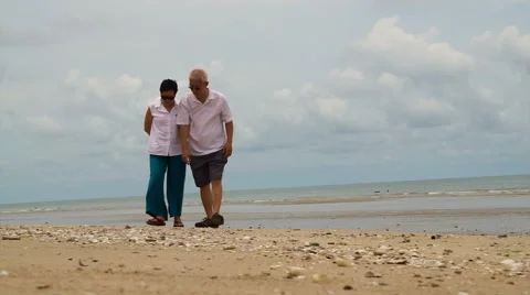 Asian elderly couple collecting shells on the beach Video stock 68585415