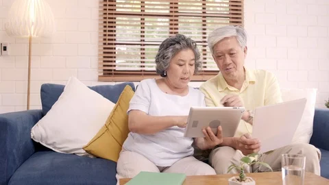 Asian elderly couple using tablet watching TV in living room at home. Stock Footage 102136347