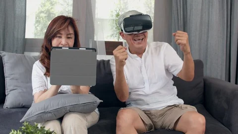 Asian elderly couple using tablet and virtual reality simulator playing games. Stock Footage 111288612