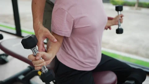 Asian elderly couple workouts together in a fitness center, focusing on strength Stock Footage 321927243