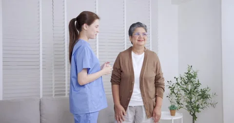 Asian elderly female guided by young Caucasian physiotherapist performing light Video stock 336306500
