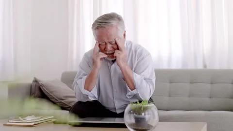 Asian Elderly have a headache. On the sofa in the living room Stock Footage 153784459