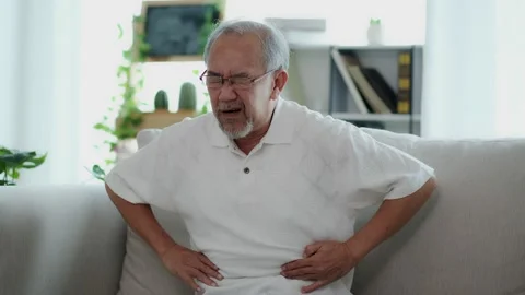 The Asian elderly man sit on sofa has a stomach ache. Caused by illness due t Stock Footage 153228780