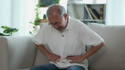 The Asian elderly man sit on sofa has a stomach ache. Caused by illness due t Stock Footage 153246390