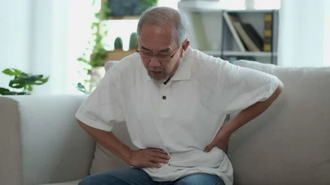 The Asian elderly man sit on sofa has a stomach ache. Caused by illness due t Stock Footage 153247204