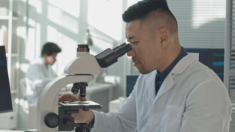 Asian Electronics Engineer Inspecting Computer Chip under Microscope Video stock 195335085