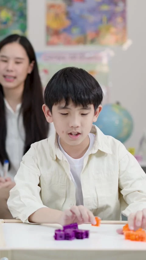 Asian Elementary School Boy Counting Colorful Building Blocks in Classroom Vídeos de archivo 334355676