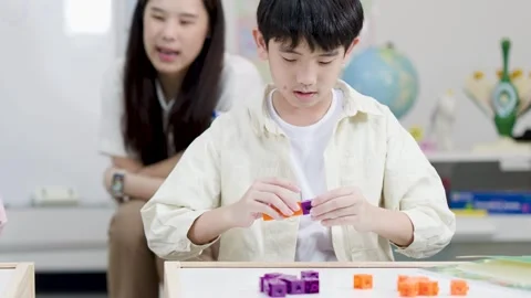 Asian Elementary Student Counting Math Blocks with Teacher in Bright Classroom Stock Footage 334355611