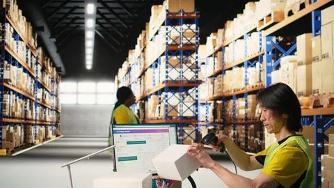 Asian employee using scanner to register shipping labels on cardboard boxes Stock Photos