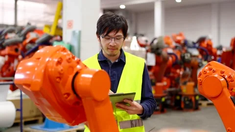 Asian engineer checking robots in a factory Stock Footage 260577398