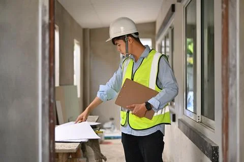 Asian engineer man planning development details, examining plans at construction Stock Photos