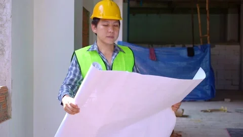 Asian engineer or Young Architect put on a helmet for safety and look at Blue Stock Footage 204080004