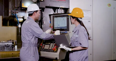 Asian engineer pair studies CNC control panel and laptop, checking program data, Stock Footage 342923330