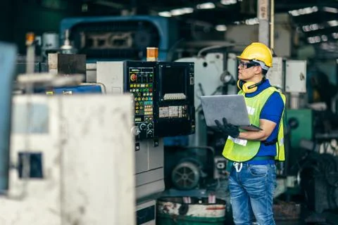 Asian engineer programming the machine in factory with laptop computer to set Foto stock