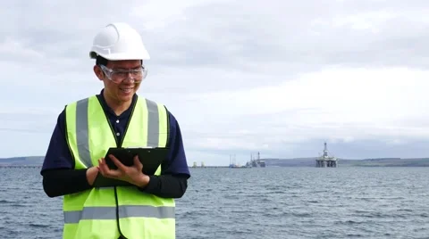 Asian engineer standing in front of semi submersible oil rig Stock Footage 63113292