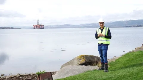 Asian engineer standing in front of semi submersible oil rig Stock Footage 63126968