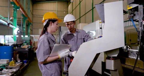 Asian engineer team checks machine panel with tablet, reviewing program data, Stockbeeldmateriaal 337285321