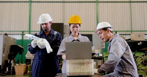 Asian engineer team reviews molded component beside laptop on shop floor, Stock Footage 342922411