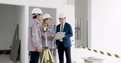 Asian engineer team studies blueprint beside survey equipment, reviewing Stock Footage 336954544