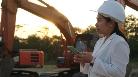 Asian engineer wearing a white helmet using a smartphone in a workplace. Stock Footage 229707331