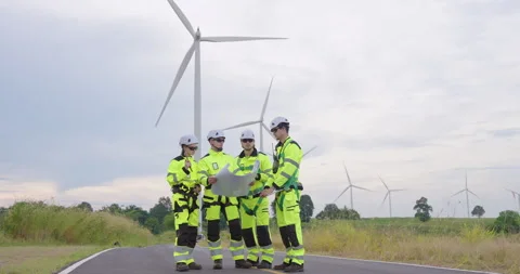 Asian engineers studying blueprint on wind farm road, teamwork reviewing Stock Footage 328695389