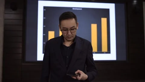 Asian expert in glasses using smartphone during presentation in conference hall Stock Footage 293734910