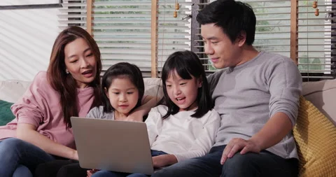 Asian family enjoy using computer together sit on sofa at home. Stock Footage 130231917
