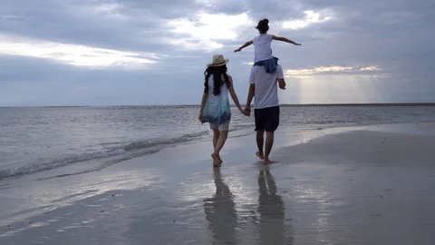 Asian family held hands walking along the sandy beach on Holidays Stock Footage