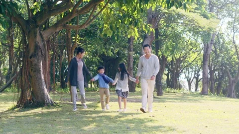 Asian family with two children walking in park Stock Footage