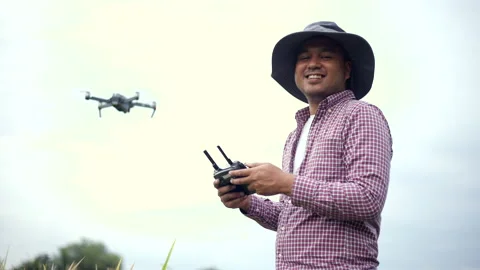 Asian farmer using drone flying navigating above farmland rice field. Stock Footage 172189359