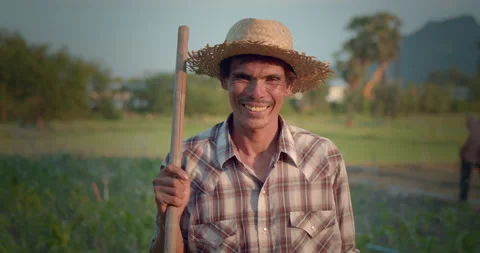 Asian farmer who is indigenous, wearing a straw hat, holding a hoe Stock Footage