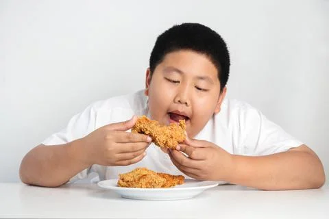 Asian fat boy eats fried chicken Wear a white shirt. 库存照片