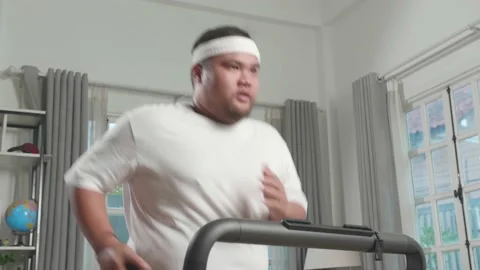 Asian Fat Man Running On A Treadmill At Home Stock Footage
