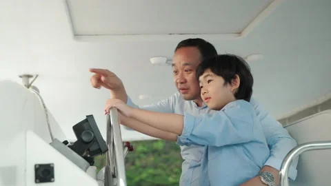 Asian father teaching son to steer a yacht, holiday activities Stock Footage 167656649