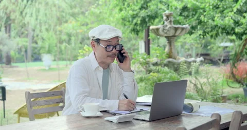 Asian father writes notes during supplier phone call, checking cafe paperwork, Stock Footage 335561752