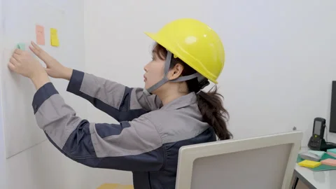 Asian female construction worker is writing or sticking note message Stock Footage 328019834