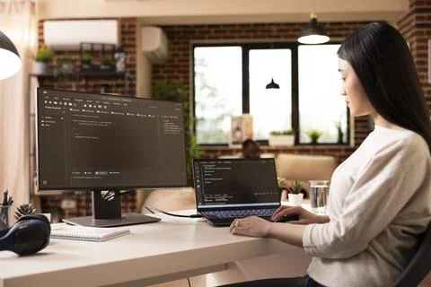 Asian female developer programming on laptop in home office 스톡 사진