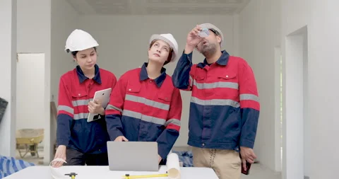 Asian female engineer leads building site discussion with inspector and Stock Footage 336536550