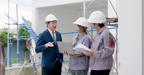 Asian female engineer listens while male manager explains blueprint updates to Stock Footage 336955724