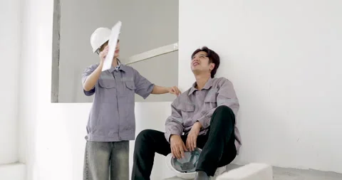 Asian female engineer points across unfinished room while holding project 库存影片 338222312