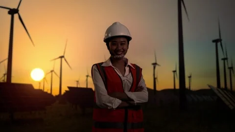 Asian Female Engineer Smiles Posing Arms Crossed In The Wind Turbines Rotating Stock Footage 255856732