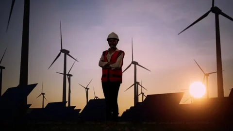 Asian Female Engineer Smiles Posing Arms Crossed In The Wind Turbines Rotating Stock Footage 255857739