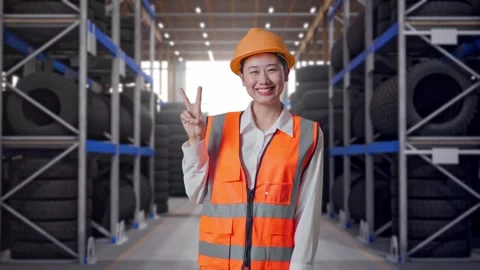Asian Female Engineer Smiling And Showing Peace Gesture at Tire Warehouse Stock Footage 341788121