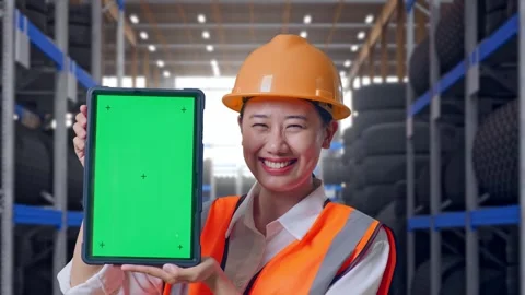 Asian Female Engineer Smiling And Showing Green Screen Tablet at Tire Warehouse Stock Footage 341788562
