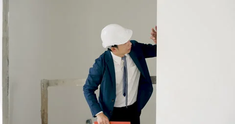 Asian female engineer wearing white helmet reviews orange folder, pointing Stock Footage 336536003