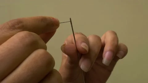 Asian female hand putting thread on needle for stitching cloth isolated light Stock Footage 166613824