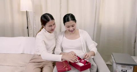 Asian female hands tiny red baby shoes to pregnant woman smiling with joy while Stock Footage 320662256