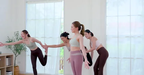 Asian female instructor steps closer as women finish dancer pose, offering Stock Footage 337452225
