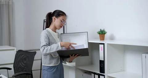 Asian female opening file folder and flipping through documents while standing Stock Footage 333607133